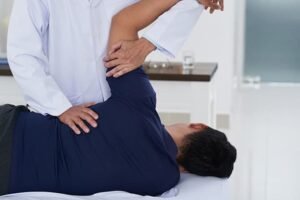 chiropractor examining male patients shoulder